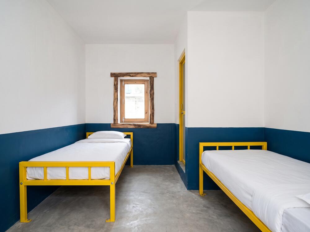 The private twin room, two single beds against whitewashed walls with a window onto the pines