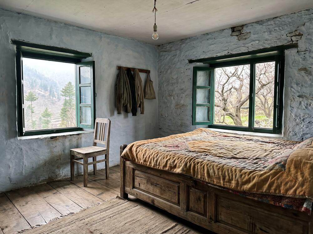 The Front Room, with a wooden bed, a window onto the valley and a window onto the orchard